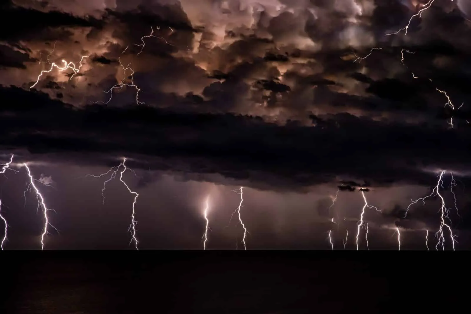 Dramatic lightning storm over dark ocean waters.